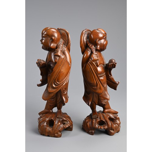 198 - A PAIR OF CHINESE CARVED WOODEN FIGURES, EARLY 20TH CENTURY. A mirrored pair each holding a bat and ... 