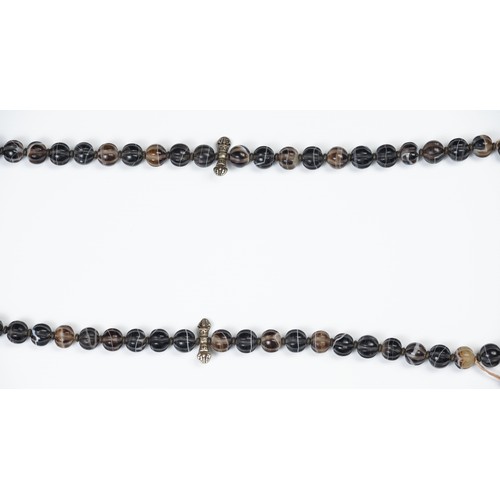 112 - A LARGE TIBETAN AGATE BEADED NECKLACE. Composed of carved dark agate beads with  ceramic spacers and... 