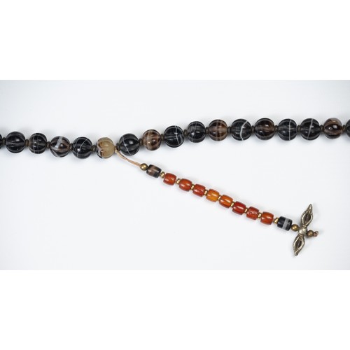 112 - A LARGE TIBETAN AGATE BEADED NECKLACE. Composed of carved dark agate beads with  ceramic spacers and... 