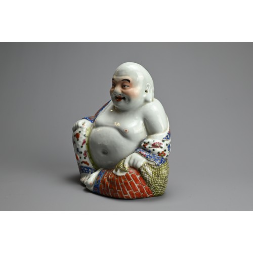 71 - A CHINESE FAMILLE ROSE PORCELAIN FIGURE OF BUDAI, 20TH CENTURY. The laughing Buddha seated dressed i... 