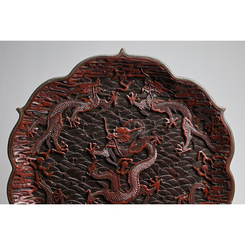 86 - A CHINESE RED LACQUER DRAGON DISH, 20TH CENTURY. With bracket lobed rim finely carved in relief with... 