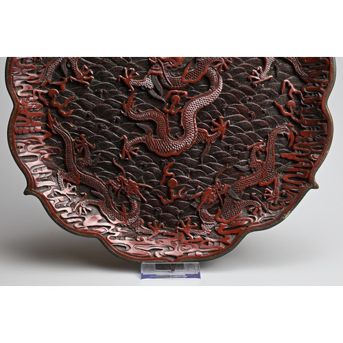 86 - A CHINESE RED LACQUER DRAGON DISH, 20TH CENTURY. With bracket lobed rim finely carved in relief with... 