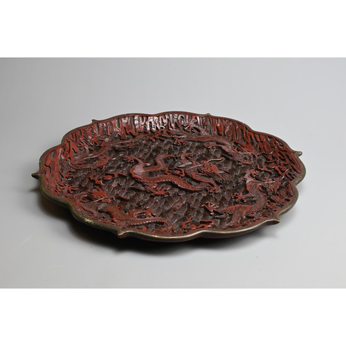 86 - A CHINESE RED LACQUER DRAGON DISH, 20TH CENTURY. With bracket lobed rim finely carved in relief with... 