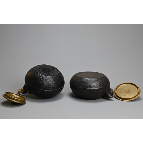 87 - TWO JAPANESE CAST IRON TEAPOTS WITH BRONZE HANDLES, 20TH CENTURY. One decorated in relief with the t... 