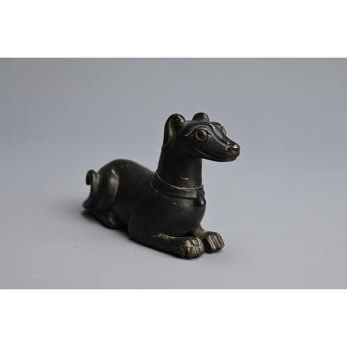 3 - A CHINESE BRONZE PAPERWEIGHT, QING DYNASTY. In the form of a recumbent dog, front facing wearing a c... 