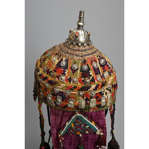 110 - A TURKMEN TRIBAL WOMEN'S HEADDRESS, 20TH CENTURY. The white metal and gilt top section inlaid with c... 