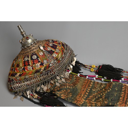 110 - A TURKMEN TRIBAL WOMEN'S HEADDRESS, 20TH CENTURY. The white metal and gilt top section inlaid with c... 