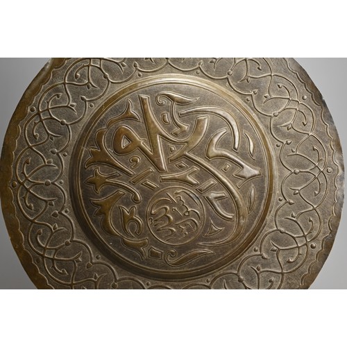 120 - A LARGE ISLAMIC BRONZE CIRCULAR PLAQUE. With central roundel with script surrounded by a band of scr... 