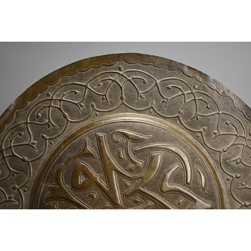 120 - A LARGE ISLAMIC BRONZE CIRCULAR PLAQUE. With central roundel with script surrounded by a band of scr... 