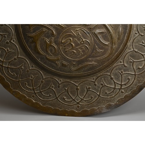 120 - A LARGE ISLAMIC BRONZE CIRCULAR PLAQUE. With central roundel with script surrounded by a band of scr... 