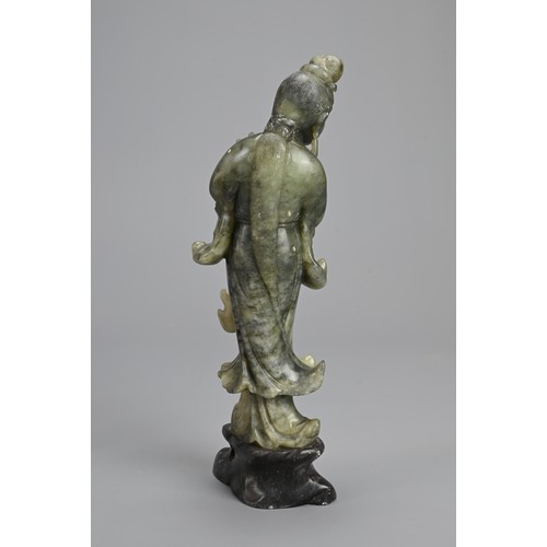 36 - A CHINESE SOAPSTONE CARVING OF GUANYIN, 20TH CENTURY. Standing dressed in robes holding lotus stems.... 