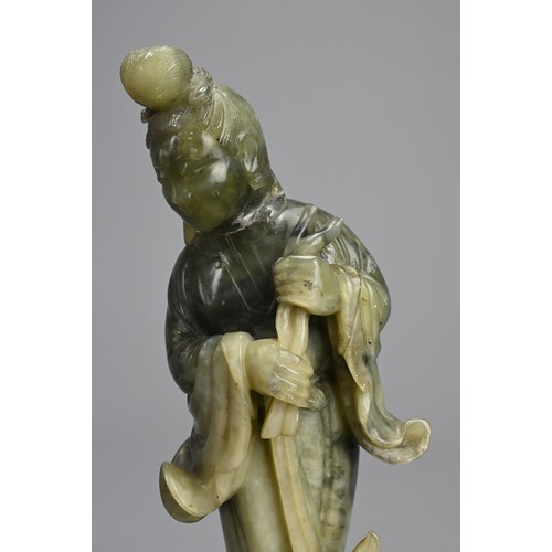 36 - A CHINESE SOAPSTONE CARVING OF GUANYIN, 20TH CENTURY. Standing dressed in robes holding lotus stems.... 