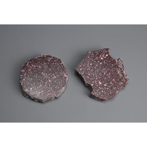 41 - TWO PORPHYRY STONE FRAGMENTS. One polished to both faces, the other polished to one face with a hole... 