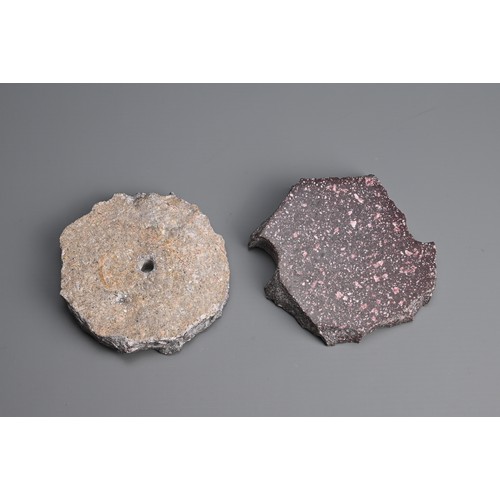 41 - TWO PORPHYRY STONE FRAGMENTS. One polished to both faces, the other polished to one face with a hole... 