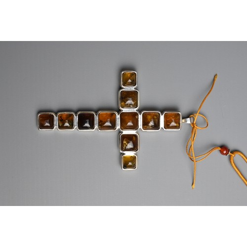 43 - A BURMESE AMBER AND WHITE METAL CROSS PENDANT. With eleven amber cabochons mounted in white metal cr... 