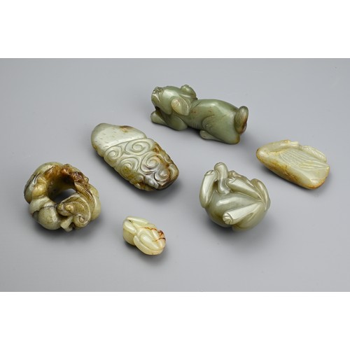 124 - SIX CHINESE CELADON JADE CARVINGS. Comprising: a model of a lion dog, a stylised goose, a small pale... 