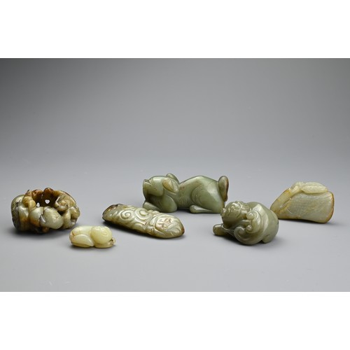 124 - SIX CHINESE CELADON JADE CARVINGS. Comprising: a model of a lion dog, a stylised goose, a small pale... 