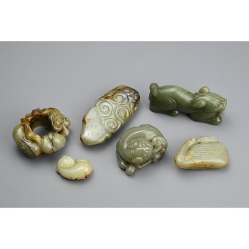 124 - SIX CHINESE CELADON JADE CARVINGS. Comprising: a model of a lion dog, a stylised goose, a small pale... 