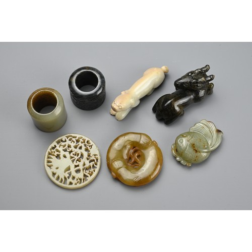 127 - SEVEN CHINESE CARVED JADE ITEMS. Comprising: a celadon stylised fish pendant, a circular pendant pie... 