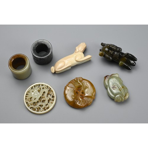 127 - SEVEN CHINESE CARVED JADE ITEMS. Comprising: a celadon stylised fish pendant, a circular pendant pie... 