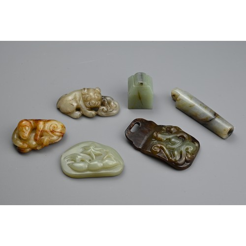 129 - SIX CHINESE JADE CARVINGS. Comprising: a celadon jade pendant depicting a trees in landscape, a dark... 