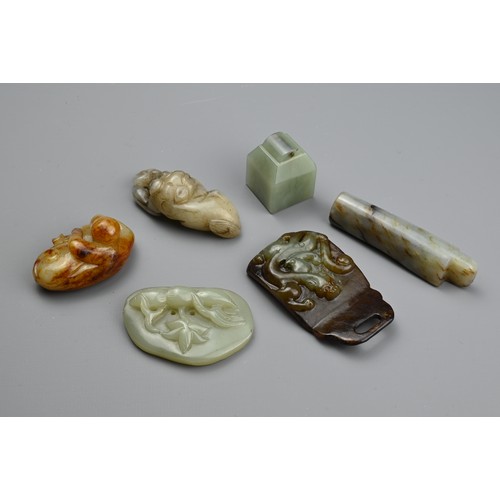 129 - SIX CHINESE JADE CARVINGS. Comprising: a celadon jade pendant depicting a trees in landscape, a dark... 