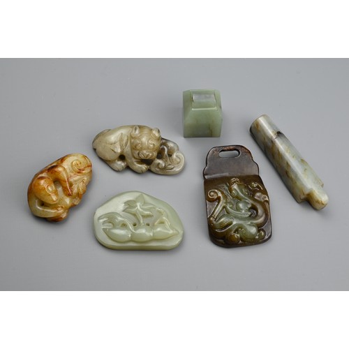 129 - SIX CHINESE JADE CARVINGS. Comprising: a celadon jade pendant depicting a trees in landscape, a dark... 