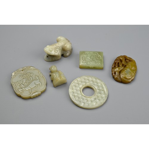 131 - SIX CHINESE CARVED JADE PENDANTS. Comprising: a pale jade disc, a cloud-shaped pendant carved with a... 