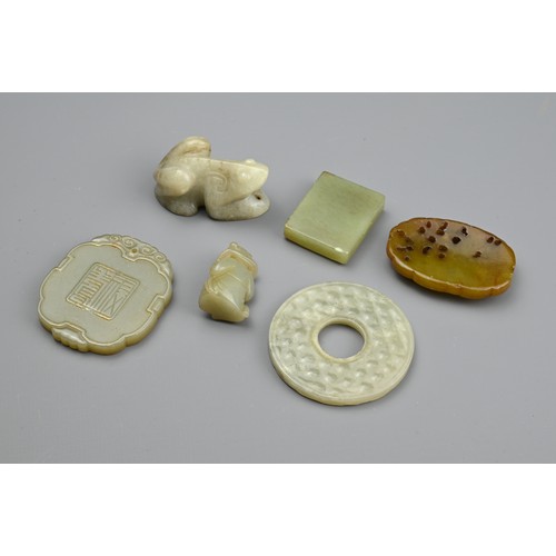 131 - SIX CHINESE CARVED JADE PENDANTS. Comprising: a pale jade disc, a cloud-shaped pendant carved with a... 