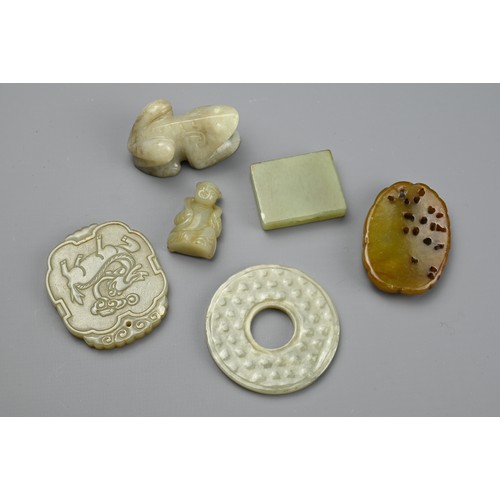 131 - SIX CHINESE CARVED JADE PENDANTS. Comprising: a pale jade disc, a cloud-shaped pendant carved with a... 