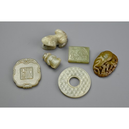 131 - SIX CHINESE CARVED JADE PENDANTS. Comprising: a pale jade disc, a cloud-shaped pendant carved with a... 