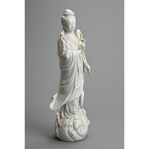 17 - A CHINESE BLANC DE CHINESE PORCELAIN FIGURE OF GUANYIN, 20TH CENTURY. Dressed in robes holding a lot... 