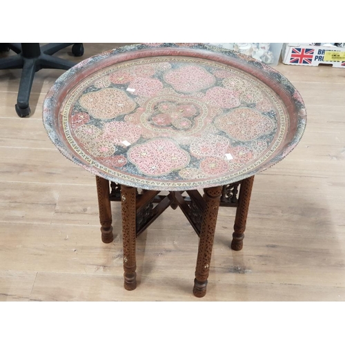 433 - A MIDDLE EASTERN BRASS CIRCULAR TRAY ON CARVED WOODEN STAND 62CM DIAMETER