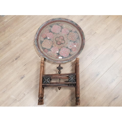 433 - A MIDDLE EASTERN BRASS CIRCULAR TRAY ON CARVED WOODEN STAND 62CM DIAMETER