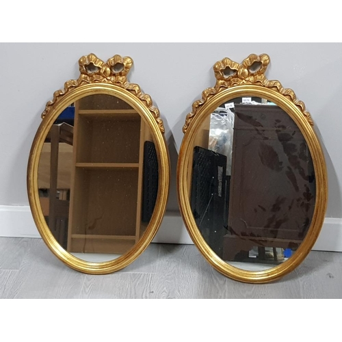 147 - PAIR OF GILT FRAMED OVAL SHAPED MIRRORS, WITH BOW DESIGN TOP, 61 X 38CM