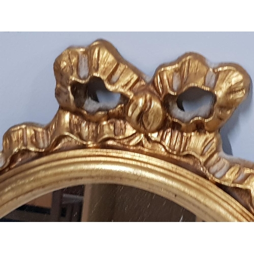 147 - PAIR OF GILT FRAMED OVAL SHAPED MIRRORS, WITH BOW DESIGN TOP, 61 X 38CM