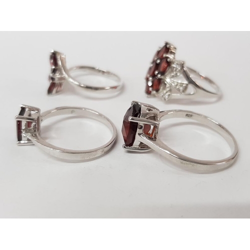 45 - FOUR SILVER AND RED STONE RINGS STAMPED SIZES T T 1/2 AND U 16G GROSS