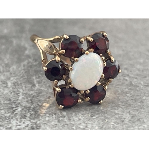 228 - 9CT GOLD OVAL OPAL AND SIX GARNET SET CLUSTER RING HALLMARKED LONDON 1977 SIZE P 5.9G