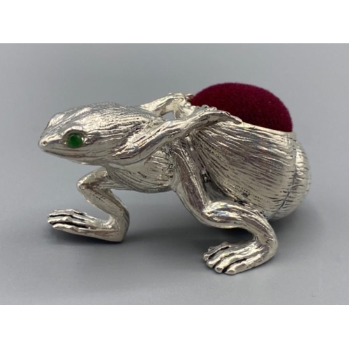 95 - A silver plated pin cushion in the form of a frog with emerald eyes, 26.1g