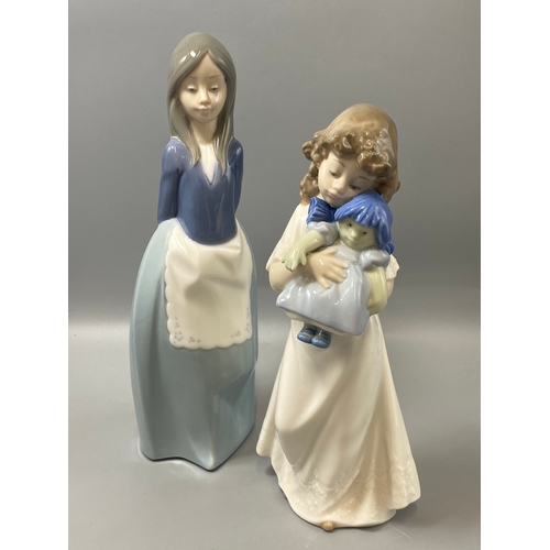 212 - 2x Nao by lladro figures girl with doll and girl politely standing both in good condition