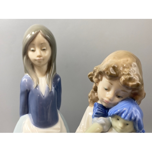 212 - 2x Nao by lladro figures girl with doll and girl politely standing both in good condition