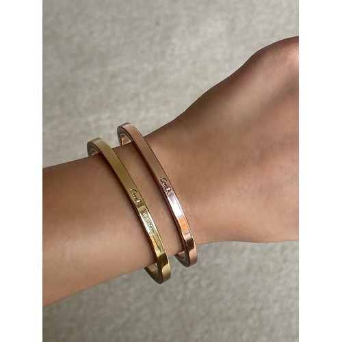 10 - Pair of bangles by Coach, one gold tone and the other rose, weighing 73.3 grams collectively