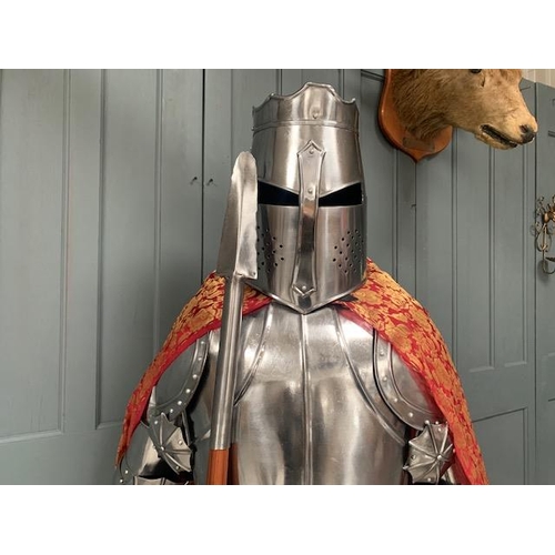 223 - HUGE MEDIEVAL DECORATIVE SUIT OF ARMOUR IN POLISHED STEEL WITH WITH SHIELD IN RED ROBE