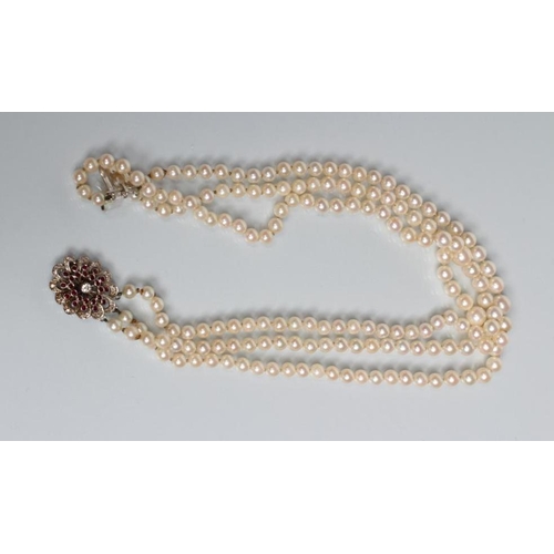 167 - A TRIPLE STRAND CULTURED PEARL NECKLACE, the knotted pearls set to an unmarked white metal open flow... 