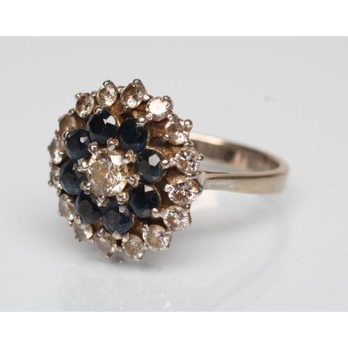 171 - A SAPPHIRE AND DIAMOND CLUSTER RING, the central diamond claw set to a border of eight facet cut sap... 