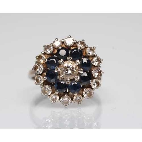 171 - A SAPPHIRE AND DIAMOND CLUSTER RING, the central diamond claw set to a border of eight facet cut sap... 