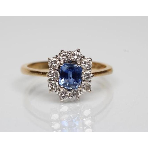 175 - A SAPPHIRE AND DIAMOND CLUSTER RING, the square cut sapphire claw set to a border of ten small round... 