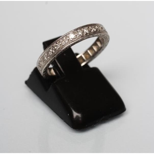 193 - A DIAMOND ETERNITY RING with point set small stones to an engraved white shank, marked 18ct, size K ... 