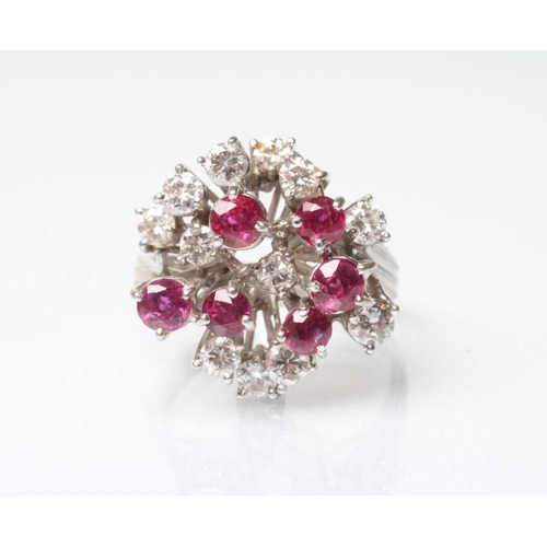 202 - A RUBY AND DIAMOND COCKTAIL RING, the open starburst claw set with six facet cut rubies and twelve b... 