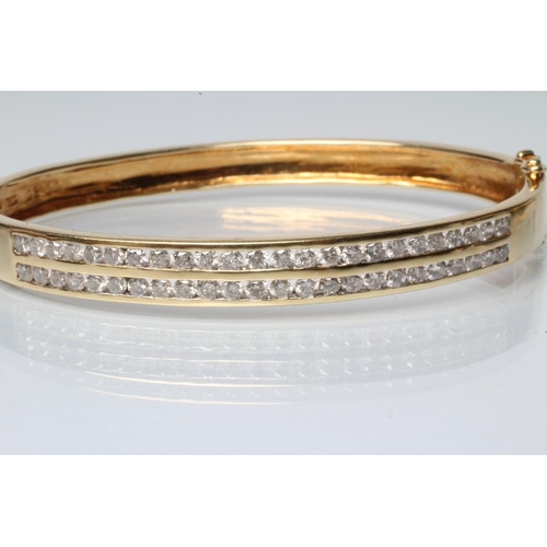 204 - A DIAMOND STIFF HINGED BANGLE, the upper section with two rows of twenty four channel set round bril... 